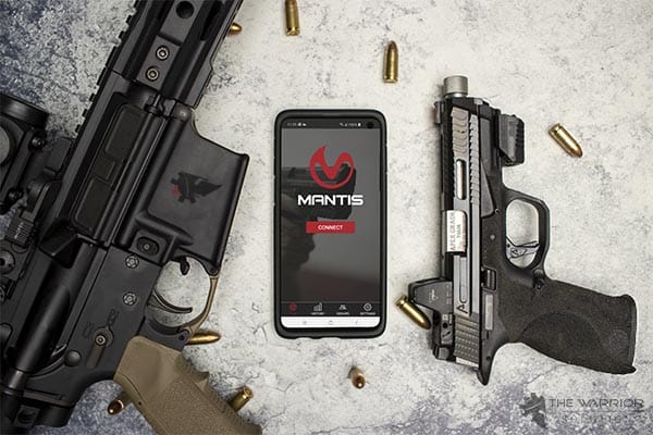 Mantis X10 on handgun with AR 15 on a table